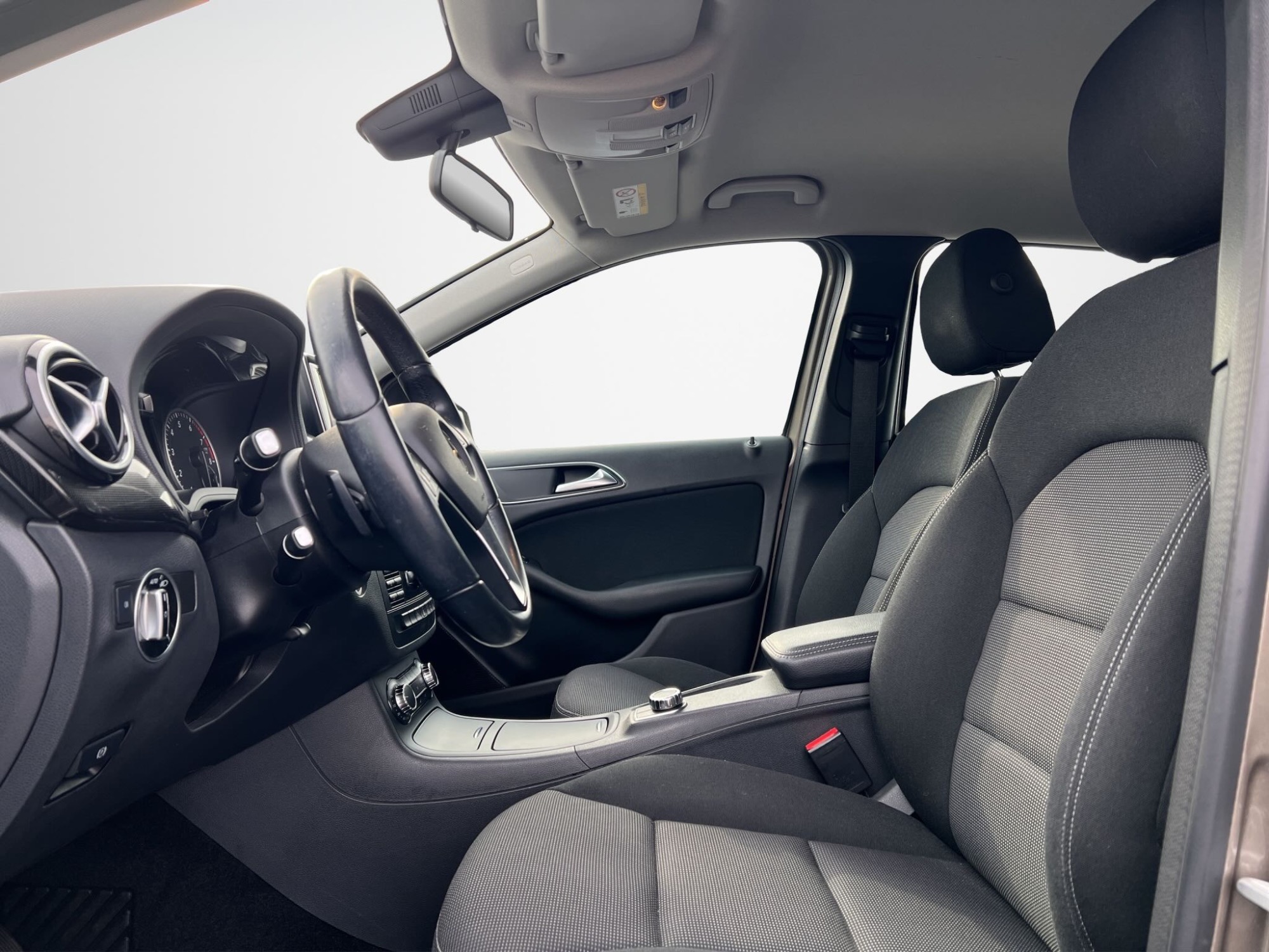 Innenansicht eines modernen Autos mit schwarzem Polster und Steuerungselementen.